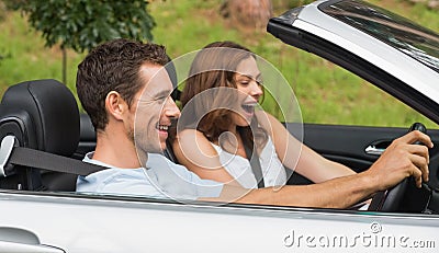 Laughing couple driving in a silver convertible