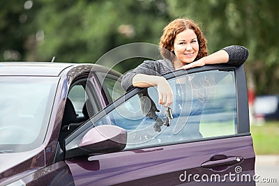 Laughing happy woman standing near new car