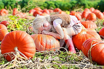 Laughing small girl playing on pumpkin field