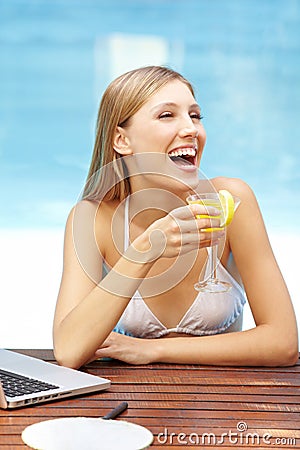 Laughing woman with cocktail in pool