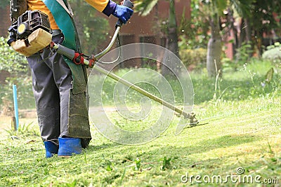 Lawn mower worker cutting grass in green field