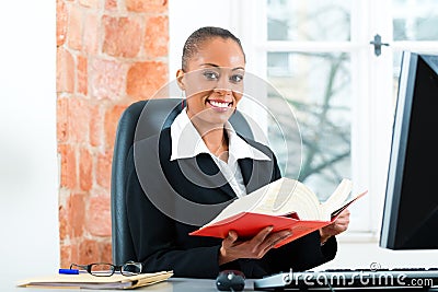 Lawyer in her office with law book on computer