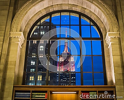 Lighted Empire State Building as viewed through window of New York Public Library Reading Room, on a winter afternoon