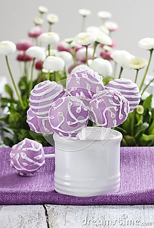 Lilac cake pops in white ceramic jar. White and pink daisies