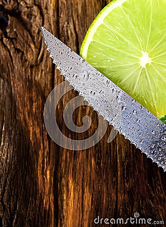Lime and knife. On wooden board.