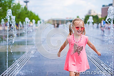 Little adorable girl have fun in street fountain