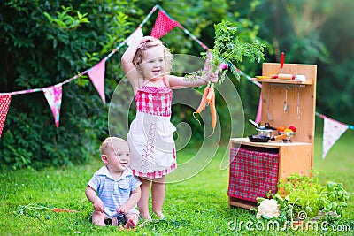 Little adorable kids playing with toy kitchen in the garden