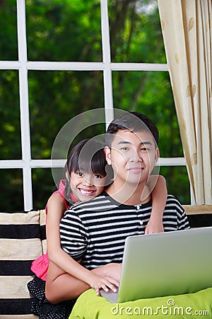 Little asian girl pointing on laptop with big brother