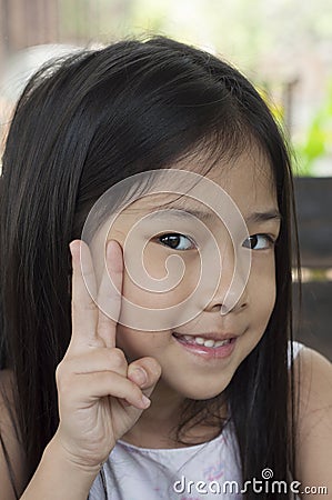 Little Asian girl with victory hand sign.
