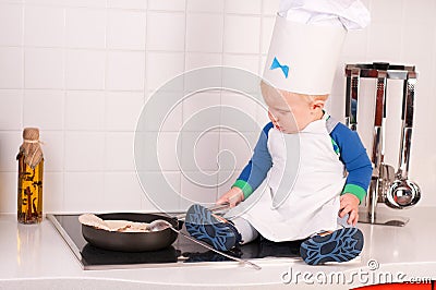 Little baby chef in the cook hat making pancakes