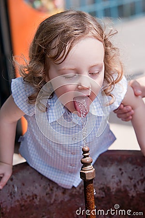 Little baby girl drinking water from a fountain