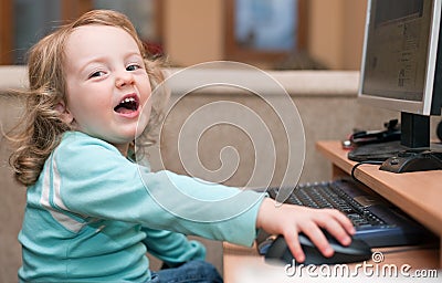 Little baby girl using a desktop computer, smiling