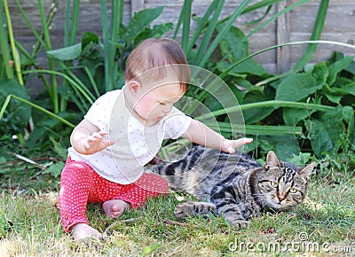 Little baby playing with cat in the garden
