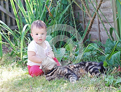 Little baby playing with cat in the garden