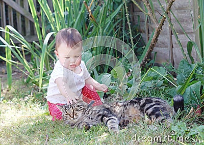 Little baby playing with cat in the garden