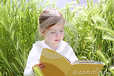 Little blond girl reading book green spikes garden