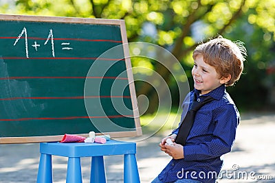 Little boy at blackboard practicing mathematics