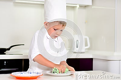 Little boy chef cleaning his plates while cooking