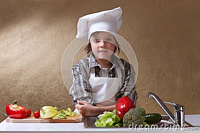 Little boy with chef hat washing vegetables