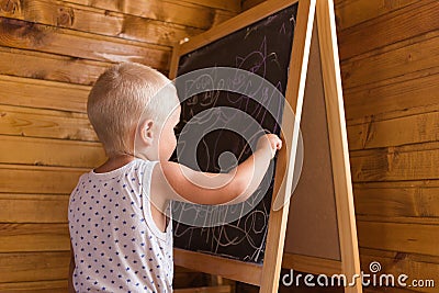 Little boy drawing with chalk on a blackboard