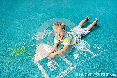 Little boy drawing chalk image on the ground