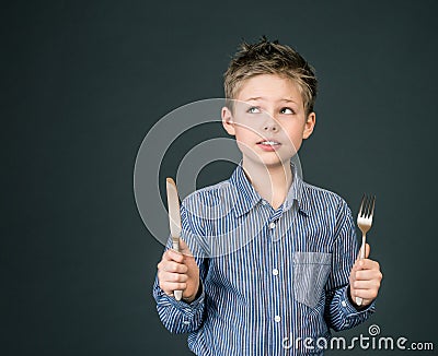 Little boy with fork and knife. Hungry child.