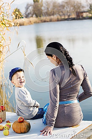 Little boy with her mother on the autumn lake