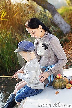 Little boy with her mother on the autumn lake