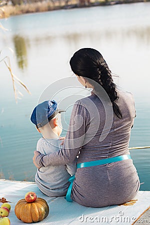 Little boy with her mother on the autumn lake