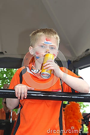 Boy in orange outfit and Dutch flags on his face