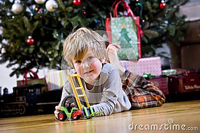 Little boy playing with toy by Christmas tree