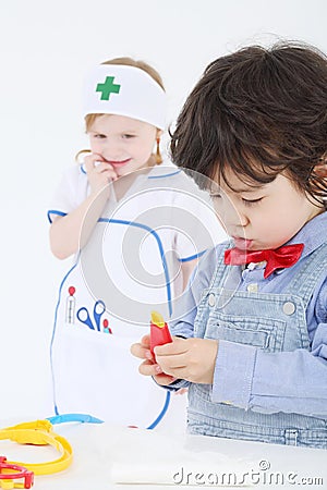 Little boy plays with toy medical instruments and girl looks