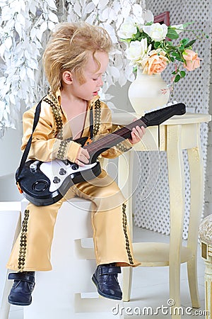 Little boy in pop retro suit playing the guitar
