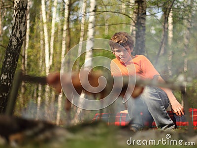 Little boy sits near campfire