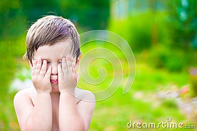 Little child is playing hide-and-seek hiding face
