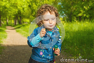 Little curly girl with soap bubbles