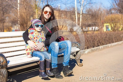 Little cute girl relax with young mother at sunny day in the city