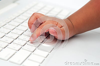 Little finger of a kid typing on keyboard