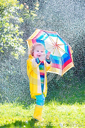 Little funny toddler with umbrella playing in rain