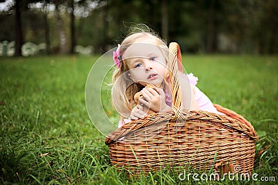 Little girl in a beautiful dress in a basket in a summer pa