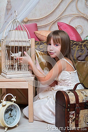 Little girl in the bedroom playing with a bird