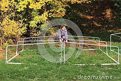 Little girl climbing on football wicket