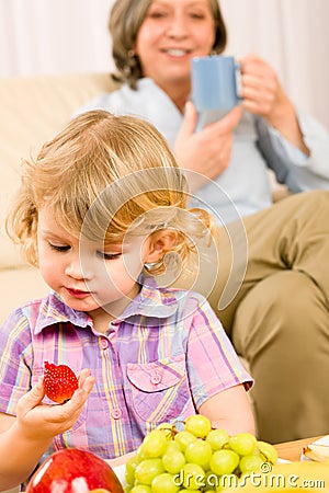 Little girl eat strawberry fruit with grandmother