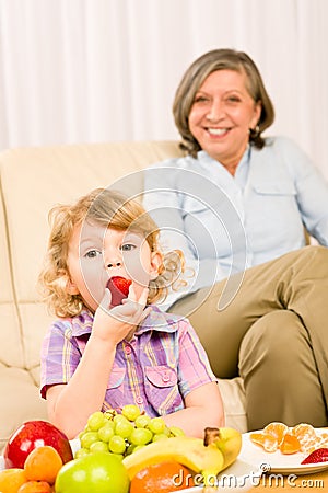 Little girl eat strawberry fruit with grandmother