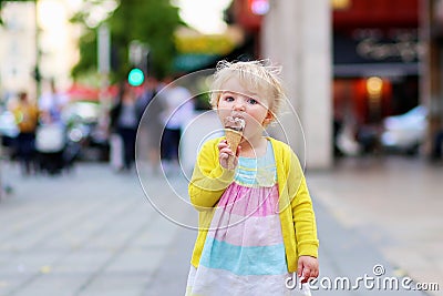 Little girl eating ice cream walking in the city