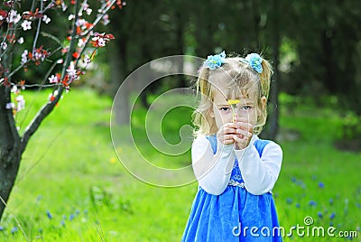 Little girl on green grass in the spring in a Blue Dress