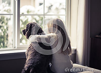 Little girl and her dog looking out the window.