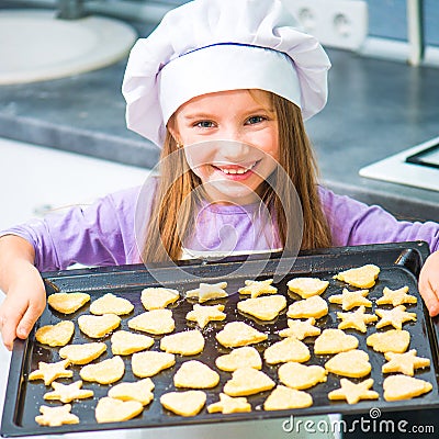 Little girl holding a baking sheet of cookies