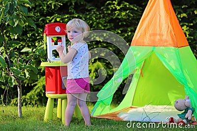 Little girl playing with toy kitchen outdoors