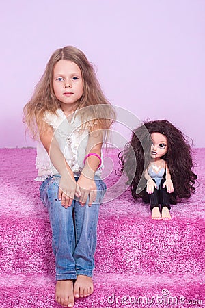 Little girl sitting on a pink bed with doll